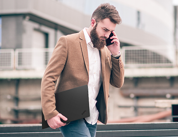 Shot of a young man carrying the lightweight ThinkPad P1 as he speaks on the phone